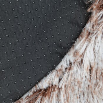 Nahaufnahme einer braun-weißen Kunstfell-Haustierdecke mit schwarzer rutschfester Punktbeschichtung auf der Rückseite.