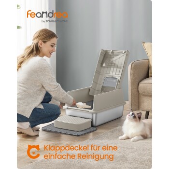 Person schaufelt Katzenstreu in eine offene feandrea-Katzentoilette; Katze steht daneben. Text: feandrea; 'Klappdeckel für eine einfache Reinigung'.