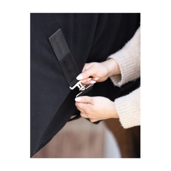 Eine Person, die eine schwarze Haustierdecke mit einem Clip befestigt, wobei die weiche Textur der Decke und ein Lederanhänger mit dem Markenlogo gezeigt werden.