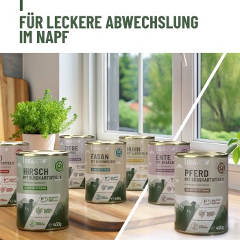 Dosen mit Tierfutter auf einem Holztisch, die Geschmäcker wie Hirsch, Huhn und Rind präsentieren, mit "Leckere Abwechslung im Napf."