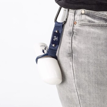 Eine Person, die graue Jeans trägt, hat eine weiße Haustierproduktflasche mit einem blauen Riemen und Clip an ihrer Taille befestigt.