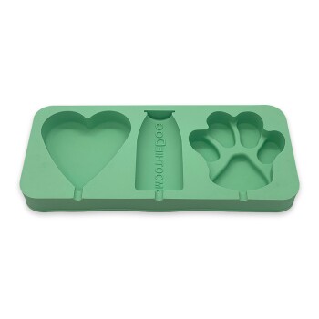 Silikon-Eisform für Hundeleckerlis mit Herz-, Flaschen- und Pfotenformen; enthält Text über die Herstellung von Hundeis und eine Kaustick-Funktion.