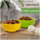 Zwei bunte Schalen, gefüllt mit Haustierfutter, eine gelbe und eine grüne, mit Textetiketten "100% Fleisch" und "100% natürlich" auf einem rustikalen Hintergrund.