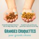 Des mains tiennent deux types de croquettes pour chien : des croquettes plus petites à gauche et des croquettes plus grandes pour les grands chiens à droite, avec des étiquettes de taille.
