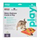 Eine Katze spielt mit dem Melon Madness Puzzle & Play Spielzeug von Petstages, das bunte Teile und einen Text enthält, der die Vorteile für neugierige Katzen hervorhebt.