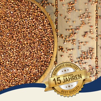 Braune Samen in einer Holzschüssel mit verstreuten Samen auf einer Holzoberfläche, mit einem Abzeichen, das "Beste Qualität - seit über 15 Jahren" liest.