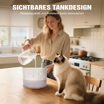 Frau gießt Wasser in einen transparenten Trinkwassertank für Haustiere auf einem Tisch, während eine flauschige Katze zuschaut; sichtbarer Text 'SICHTBARES TANKDESIGN'.