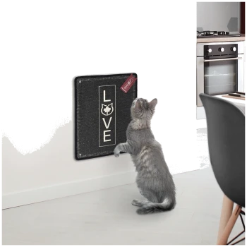 Eine graue Katze steht auf ihren Hinterbeinen und greift nach einem schwarzen, an der Wand montierten Kratzbrett, auf dem das Wort 'LIEBE' gedruckt ist.