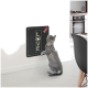 Eine graue Katze steht auf ihren Hinterbeinen und greift nach einem schwarzen, an der Wand montierten Kratzbrett, auf dem das Wort 'LIEBE' gedruckt ist.