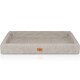Ein plüschiges, rechteckiges Haustierbett in einer sanften beige Farbe mit erhöhten Kanten und einer lederähnlichen Textur, mit einem kleinen braunen Logoetikett.