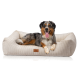 Ein glücklicher Australian Shepherd Hund liegt auf einem plüschigen, beigen Hundebett mit Cord-Textur, das ein kleines Logo-Tag hat.