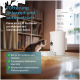 Eine Katze nähert sich einem weißen automatischen Futterspender mit einem digitalen Display, das Funktionen wie "Automatisches Füttern" und "Bis zu 10 Portionen" anzeigt.