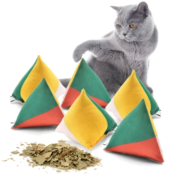 Eine graue Katze spielt mit bunten, dreieckigen Katzenminze-Spielzeugen in Gelb, Grün und Rot, mit getrockneter Katzenminze, die auf dem Boden verstreut ist.