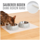 Eine Bengal-Katze frisst aus zwei grauen geometrischen Haustierschalen auf einer weißen Matte, mit dem Text "SAUBERER BODEN DANK HOHEM RAND" darüber.