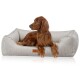 Ein brauner Irish Setter Hund, der in einem plüschigen, beigen Hundebett mit gerippter Textur und einem Lederanhänger entspannt.
