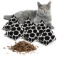 Eine graue Katze mit leuchtend orangefarbenen Augen sitzt neben fünf schwarz-weißen Katzenminzkissen und einem Haufen getrockneter Katzenminze.