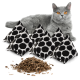 Eine graue Katze mit leuchtend orangefarbenen Augen sitzt neben fünf schwarz-weißen Katzenminzkissen und einem Haufen getrockneter Katzenminze.