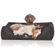 Zwei Hunde liegen auf einem dunkelgrauen Hundebett mit dem Logo "KNUFFELWUFF"; einer ist verspielt, der andere ruht sich aus.