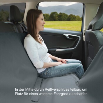 Eine Frau sitzt auf dem Rücksitz eines Autos, mit einem grauen Haustiersitzbezug, der in der Mitte einen Reißverschluss hat, um einen zusätzlichen Passagier unterzubringen.