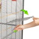 Eine Person entfernt ein Metallgitter aus einem Haustierkäfig, mit grünen Pfeilen, die die Richtung zeigen. Der Käfig hat Holzstangen und einen Fressnapf.