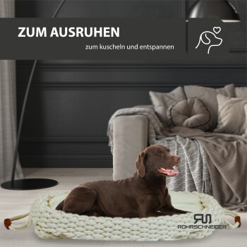 Ein entspannter brauner Hund liegt auf einem gemütlichen, gestrickten Haustierbett in einem stilvollen Wohnzimmer, mit dem Text "ZUM AUSRUHEN" und "zum kuscheln und entspannen" darüber.