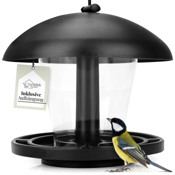 Ein schwarzer Vogelhaus mit einem klaren Behälter und einem hängenden Schild, das "wildlife home Inklusive Aufhängung" liest, neben einem bunten Kohlmeisen-Vogel.