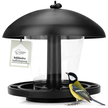 Ein schwarzer Vogelhaus mit einem klaren Behälter und einem hängenden Schild, das "wildlife home Inklusive Aufhängung" liest, neben einem bunten Kohlmeisen-Vogel.
