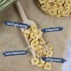 Getrocknete Bananenscheiben auf einem Holzlöffel und Teller mit deutschem Text, der natürliche, vitaminreiche und artspezifische Haustierleckerlis hervorhebt.