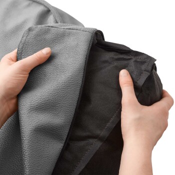 Eine Person hält einen grauen Bezug für ein Haustierbett, der teilweise geöffnet ist, um ein schwarzes Innenfutter zu zeigen, das sein abnehmbares Design präsentiert.
