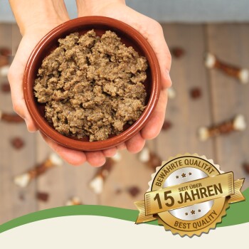 Eine Person hält eine braune Schüssel mit Haustierfutter auf einer Holzoberfläche, umgeben von Hundeleckerlis und einem "Best Quality"-Abzeichen mit der Aufschrift "15 Jahre."