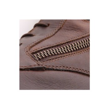 Nahaufnahme eines braunen Lederschuhs mit einem dekorativen Reißverschluss und komplizierten Nähdetails.