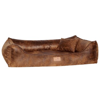 Braunes Plüsch-Haustierbett mit geschwungenem Design und einem kleinen passenden Kissen, mit einer lederähnlichen Textur und einem Logo-Patch.