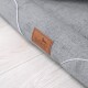 Grau Haustierbett mit einem braunen Lederetikett mit der Aufschrift "tierlando" auf einem hellen Holzboden.