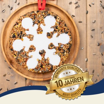 Ein runder Vogelfutterornament in Form einer Schneeflocke, dekoriert mit weißem Zuckerguss und einem roten Band, beschriftet mit "PREMIUM."