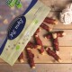 Eine teilweise geöffnete Tüte mit Haustierleckereien mit dem Etikett 'Premium Qualität' auf einer Holzoberfläche, umgeben von gerollten Leckereien, die mit Fleisch überzogen sind.