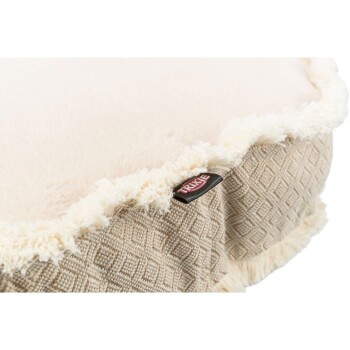 Eine Nahaufnahme eines plüschigen Haustierbettes mit einer weichen, cremefarbenen Oberseite und einer strukturierten beige gemusterten Seite, mit einem sichtbaren Trixie-Markenetikett.