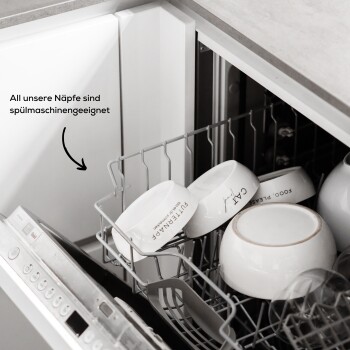 Weiße Haustierschalen, beschriftet mit "FUTTERPARADE" und "CAT" in einer Spülmaschine, mit dem Text "Alle unsere Näpfe sind spülmaschinengeeignet."