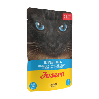 Nahaufnahme des Gesichts einer schwarzen Katze mit blauen Augen auf einer Haustierfutterverpackung, die mit "Huhn mit Lachs" und "Josera" beschriftet ist, gekennzeichnet mit "Made in Germany."