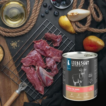 LIEBESGUT-Hundefutterdose mit der Aufschrift „Hirsch für Hunde“ neben rohem Wildfleisch auf einem Abtropfgitter, Birnen, Heidelbeeren und Öl.