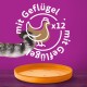La queue rayée d'un chat atteint un bol de nourriture pour animaux de compagnie orange sur un fond violet, avec un texte qui dit "mit Geflügel x12".