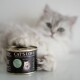Puszysta biała kotka z zielonymi oczami odpoczywa obok puszki karmy dla kotów 'CAT'S LOVE', oznaczonej dla dorosłych kotów z indykiem.