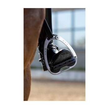 Eine Nahaufnahme des schwarzen Stiefels eines Reiters in einem silbernen Steigbügel, mit dem Markennamen "LeMieux", der auf dem Steigbügel sichtbar ist.