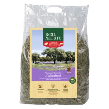Wiesenheu Südfrankreich 1,5kg Eine durchsichtige Tüte Real Nature Heu für Kleintiere, beschriftet mit "NAGER & ZIERKANINCHEN" und einer malerischen Kulisse von Bäumen und Feldern.