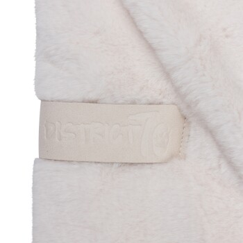 Eine Nahaufnahme einer weichen, flauschigen Haustierdecke in hellbeige, mit einem strukturierten Etikett, das 'DISTRICT 70' geprägt hat.