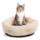 Eine getigerte Katze mit leuchtend grünen Augen sitzt aufrecht in einem plüschigen, cremefarbenen Haustierbett und zeigt seine weiche Textur und runde Form.