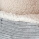 Nahaufnahme eines weichen, plüschigen Haustierbettes mit einem flauschigen cremefarbenen Innenraum und einer strukturierten grauen Außenseite.