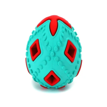 Blauer und roter strukturierter Gummihundespielzeugball mit diamantförmigen Löchern auf weißem Hintergrund.