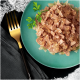 Une assiette turquoise avec de la nourriture humide pour animaux, de la viande hachée en gelée, garnie de persil, une fourchette en or et un tissu sombre.