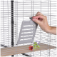 Eine Hand hält ein graues Schiebetürpaneel für einen Haustierkäfig, mit bunten Spielzeugen, die im Käfig auf einem Holzregal sichtbar sind.