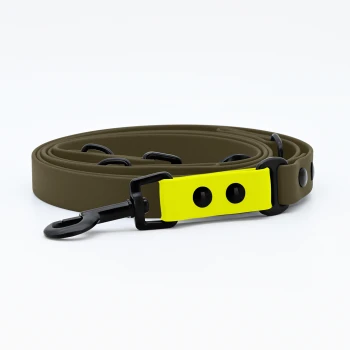 Eine braune Hundeleine mit einem leuchtend gelben Griff und schwarzen Clips, auf einem weißen Hintergrund aufgerollt.